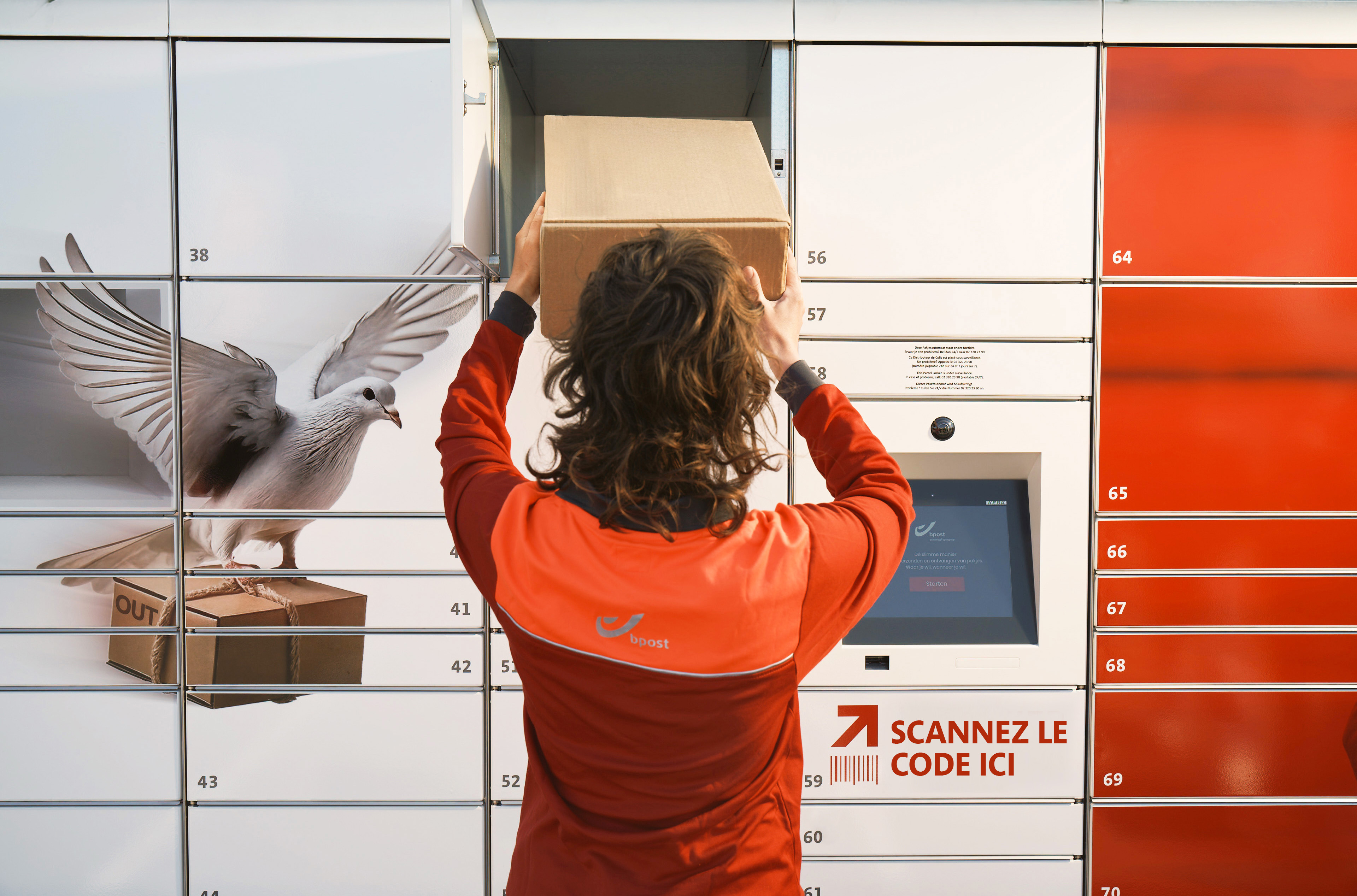 Un employé bpost qui dépose un colis dans un bbox
